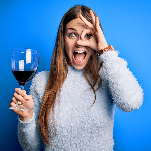 Femme humoristique tenant un verre de vin sur fond bleu